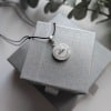 Pandantiv Dreamweaver’s Heart de 14 mm cu inimă din fire de păr și numele Dragoș pe fundal alb